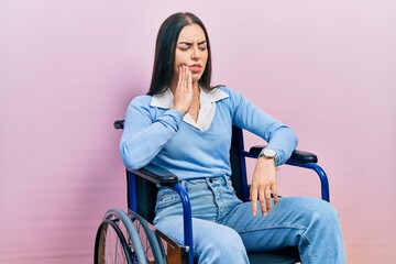 Poster - Beautiful woman with blue eyes sitting on wheelchair touching mouth with hand with painful expression because of toothache or dental illness on teeth. dentist