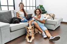 Young Hispanic Couple With Dogs Relaxing At Home With A Happy And Cool Smile On Face. Lucky Person.