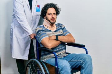 Sticker - Handsome hispanic man sitting on wheelchair wearing neck collar skeptic and nervous, disapproving expression on face with crossed arms. negative person.