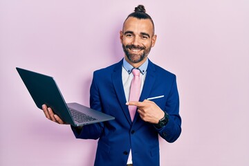 Young hispanic man working using computer laptop smiling happy pointing with hand and finger