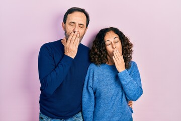 Poster - Middle age couple of hispanic woman and man hugging and standing together bored yawning tired covering mouth with hand. restless and sleepiness.