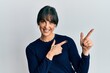 © Krakenimages.com - Young hispanic woman wearing casual clothes smiling and looking at the camera pointing with two hands and fingers to the side.