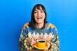 © Krakenimages.com - Young hispanic woman drinking a cup of coffee smiling and laughing hard out loud because funny crazy joke.
