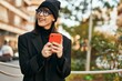 © Krakenimages.com - Young hispanic woman smiling happy using smartphone at the city.