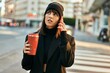 © Krakenimages.com - Young hispanic woman talking on the smartphone and drinking coffee at the city.
