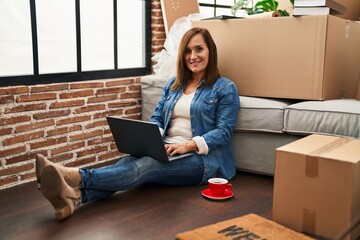 Sticker - Middle age woman using laptop sitting on the floor at new home