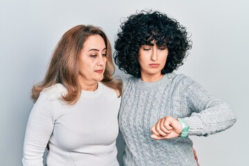 Sticker - Middle east mother and daughter wearing casual clothes checking the time on wrist watch, relaxed and confident