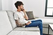 © Krakenimages.com - Young hispanic man using smartphone sitting on the sofa at home.