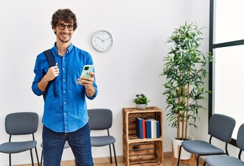 Wall Mural - Young hispanic man smiling confident using smartphone at waiting room