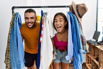 Wall Mural - Young latin couple smiling happy appearing through clothes at fashion store.