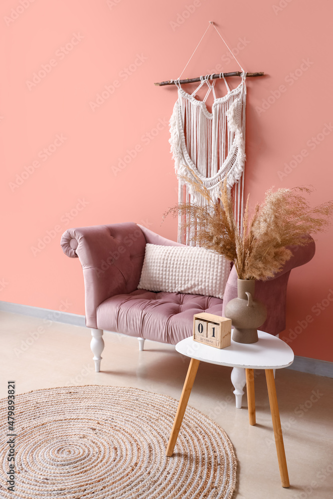 Stylish comfortable armchair with table near pink wall in room