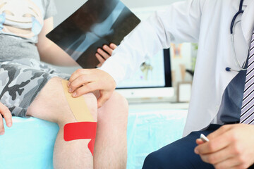 Physician wear uniform and stethoscope carefully examining patient leg