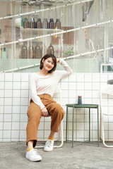 young asian woman in dress up in earth tone color sitting in front of minimal cafe.