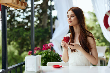 pretty woman in a white dress drinks coffee outdoors in a cafe Relaxation concept