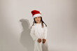 © PhotoBook - Lovely charming girl wearing white dress and Santa cap having fun over isolated background. Holiday concept