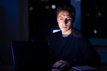 Man is working on a laptop at night.