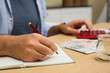© New Africa - Man counting money with calculator at table indoors, closeup