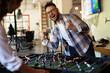 © JustLife - Colleagues having fun at work. Businessman and businesswoman playing table soccer..