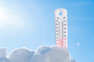 The thermometer lies on the snow in winter showing a negative temperature.Meteorological conditions in a harsh climate in winter with low air and ambient temperatures.Freeze in wintertime.Sunny winter