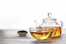A Mug Or Cup With Green Herbal Tea And A Teapot With Tea Leaves On Grey Background. Beauty Color