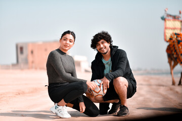 Wall Mural - young happy couple sitting on beach indian pakistani model