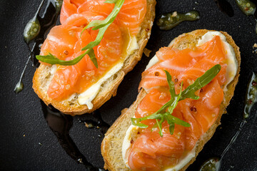 Wall Mural - Bruschetta with salmon and cheese on black plate macro close up top view