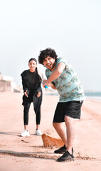 Wall Mural - young happy couple playing circket on beach indian pakistani model