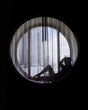 Silhouette of woman wearing hat sitting in the round window