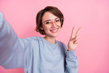 Self-portrait Of Attractive Cheerful Girl Showing V-sign Good Mood Isolated Over Pink Pastel Color Background