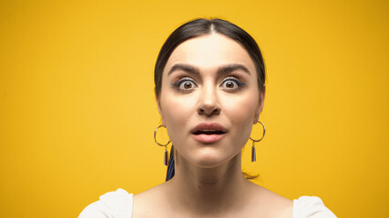 Wall Mural - Shocked brunette woman in blouse looking at camera isolated on yellow.
