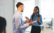 © BullRun - Happy diverse male and female colleagues discussing business strategy during coffee break in office, cheerful partners with cellphone talking about friendly brainstorming in corporate workspace