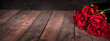 Bouquet of red roses on dark vintage planks. Horizontal background for romantc valentine's day greetings with space for text.