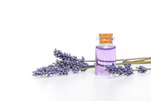 Bottle Of Essential Oil And Lavender Flowers On White Background