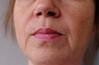 close-up part of female face of woman 40-50 years old with age wrinkles, wart over lip, concept of cosmetics, skincare, correction surgery, beauty and perfect skin, flyer for your ad antiaging