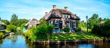 Peaceful Rural Landscape Of Giethoorn Village, The Netherlands. House With Beautiful Flowers In Small Typical Village. Landscape View Of Houses With Canals And Rustic Thatched Roof Houses.