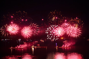 Wall Mural - Holiday fireworks above water with reflection on the black sky background