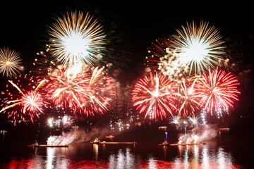 Wall Mural - Holiday fireworks above water with reflection on the black sky background