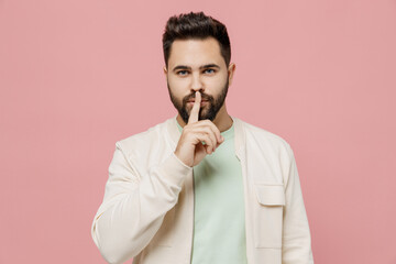 Wall Mural - Young smiling happy secret man 20s wear trendy jacket shirt say hush be quiet with finger on lips shhh gesture isolated on plain pastel light pink background studio portrait. People lifestyle concept.