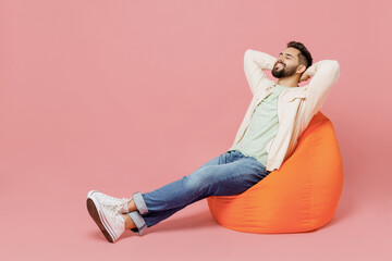 full body young smiling happy man 20s wear trendy jacket shirt sit in bag chair hold hands behind ne