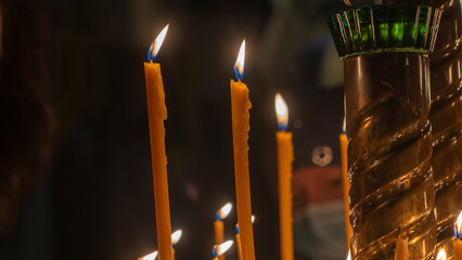 Wall Mural - Church candle light. Many burning wax candles in the orthodox church or temple. Selective focus.