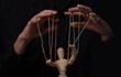 Hands manipulating wood puppet. Master of marionette.