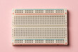 An electronics breadboard on pink background..