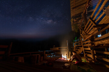 Wall Mural - female traveler sitting near campfire under night sky with stars and milky way. night camping. hikin