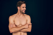© Roman - Handsome young man isolated. Portrait of shirtless muscular man is standing on dark blue background and pointing to the side. Showing product.