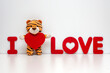 Plush tiger hugging a red heart. A gift for Valentine's Day in the Year of the Tiger. Inscription in red letters I love.