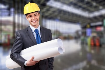 Young man architect wearing hardhat at construction site while working.