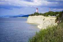High Rocky Coast Of The Black Sea. High Layered Rocks. Lighthouse On The Seashore. Blue Sea Summer, White Clouds.