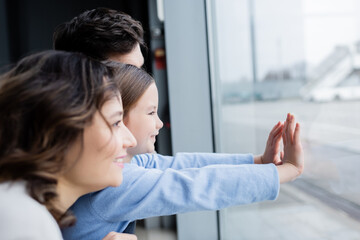 side view of cheerful family looking at window in airport.