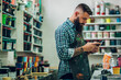 © Zamrznuti tonovi - Male worker mixing colors for screen printing in a workshop and using a smartphone