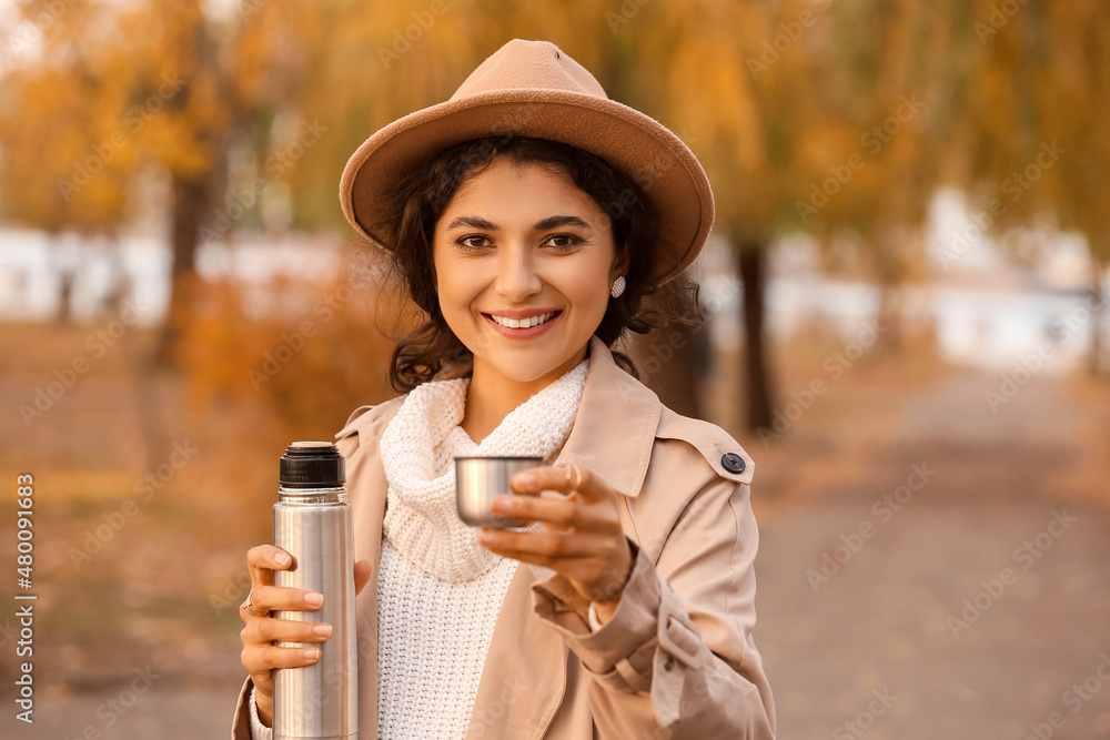 Beautiful woman with thermos drinking tea outdoors